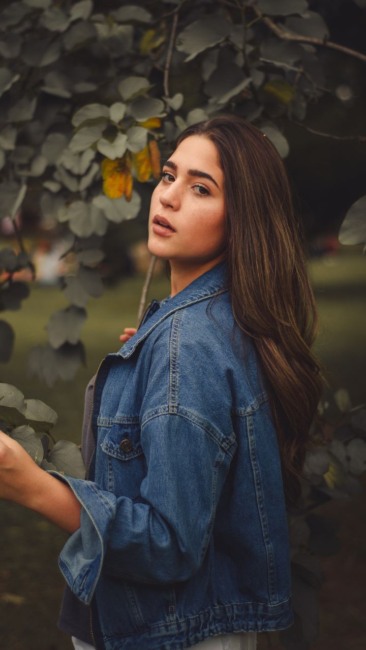 Charming young girl with beautiful hair posing for the camera in a jeans  jacket Stock Photo by ©ponomarencko 154009910